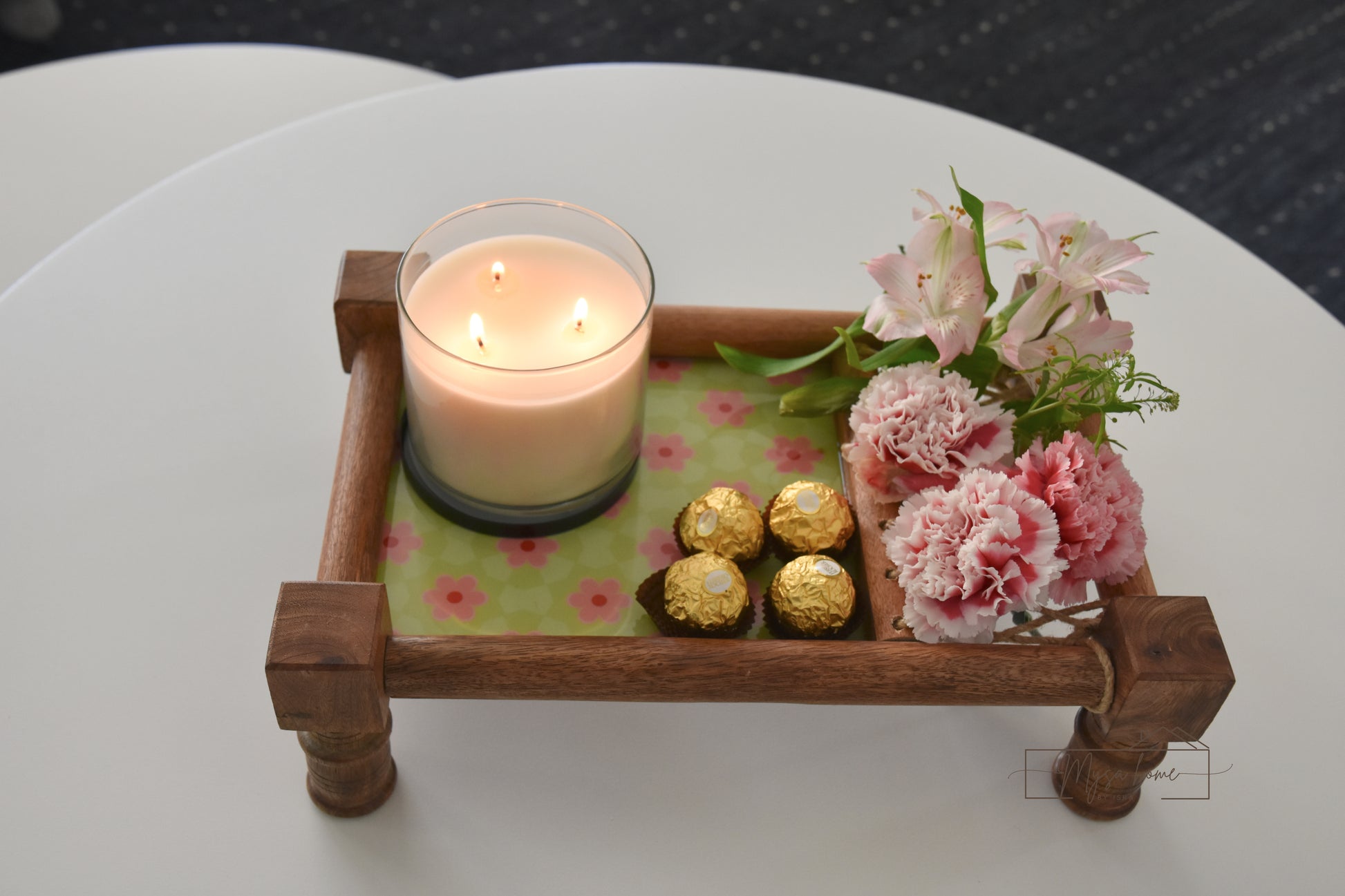 Candle, chocolates, and flowers on a decorative tray with a floral pattern